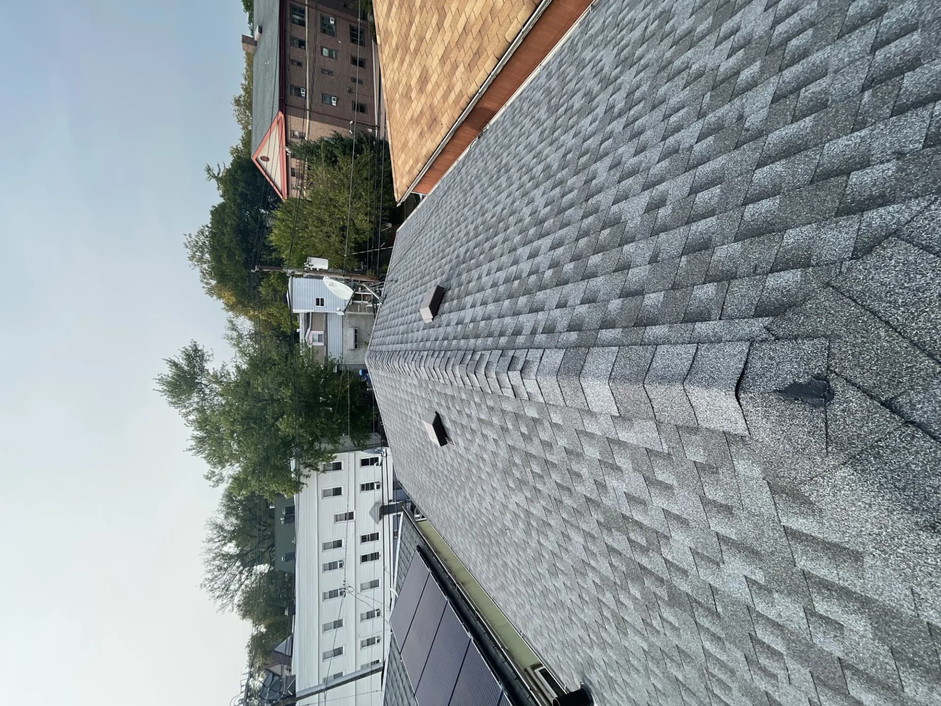 Aerial view of a completed charcoal architectural shingle roof with ridge cap on a multi-story home in New Jersey