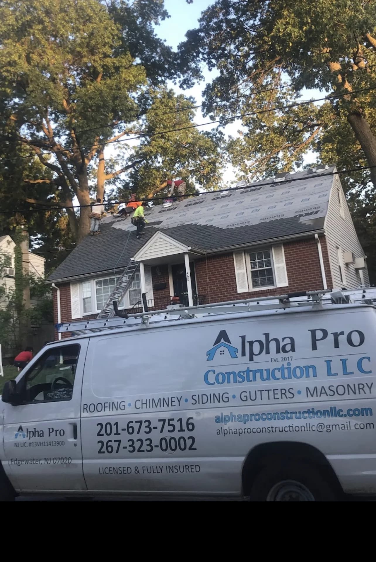 Alpha Pro Construction crew installing shingles beside the company van on a New Jersey home