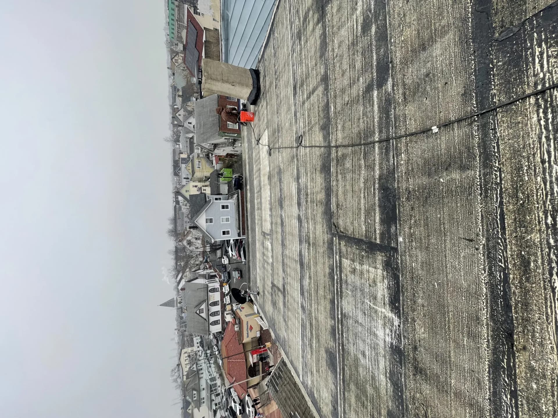 Roofer repairing shingles and flashing in a roof valley on a residential home with a service truck below in New Jersey